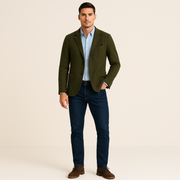 Man wearing a green blazer, blue shirt, and dark jeans on a beige background